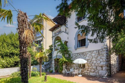 a white building with a palm tree in front of it at City Apartment With Garden - Happy Rentals in Rijeka