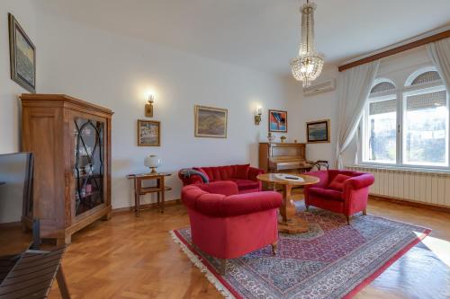 a living room with red chairs and a tv at City Apartment With Garden - Happy Rentals in Rijeka