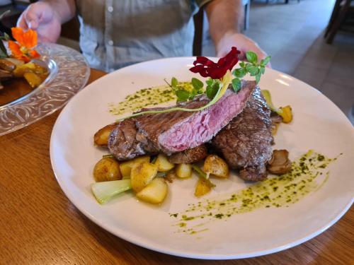 a plate of food with meat and potatoes on a table at Wohlmuth-Lückl in Kitzeck im Sausal