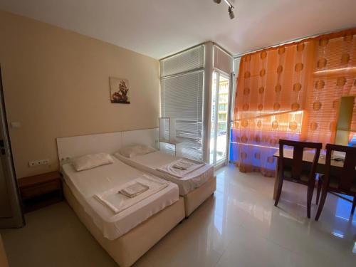 Schlafzimmer mit einem Bett, einem Tisch und einem Fenster in der Unterkunft Studios & Apartments Perla in Sonnenstrand