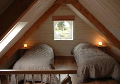 ル・コンケにあるGîtes Le Bout du Mondeのベッド2台と窓が備わる屋根裏部屋です。