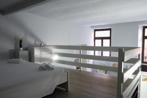 a white bedroom with a bed and a staircase at Carega City Center Apartment in Verona