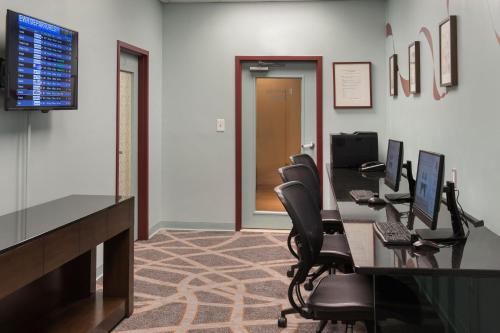 an office with a desk with chairs and a monitor at Newark Liberty International Airport Marriott in Newark