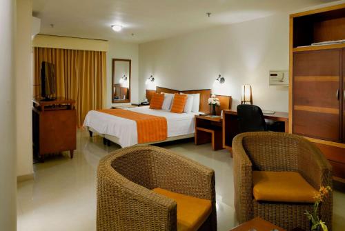 una camera d'albergo con letto, scrivania e sedie di Howard Johnson by Wyndham Barranquilla Versalles a Barranquilla
