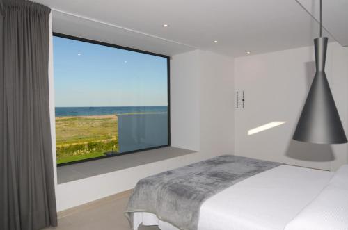 ein Schlafzimmer mit großem Fenster mit Blick auf das Meer in der Unterkunft VILLA PINELL in Torroella de Montgrí