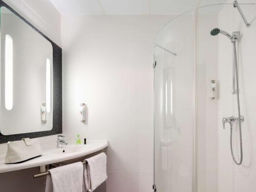 y baño blanco con lavabo y ducha. en Ibis Sevilla en Sevilla