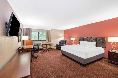 Ramada by Wyndham Grand Forks في غراند فوركس: غرفة فندقية بسرير وتلفزيون بشاشة مسطحة