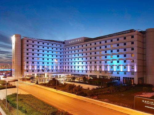 a large building with blue lights on a city street at Sofitel Athens Airport in Athens