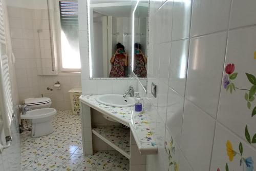 una donna che scatta una foto in uno specchio del bagno di Appartamento g&g a Nervi