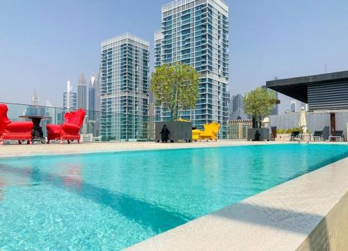 a large pool with chairs and tables in a city at Fully Furnished 3BR+ Maid’s in the heart of Dubai in Dubai