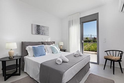 una camera bianca con un grande letto e un balcone di Secluded Elegance at Villa Giem - 4 Bedrooms - Unmatched Sea Views - Private Pool & Lush Gardens - Dassia a Dafnila