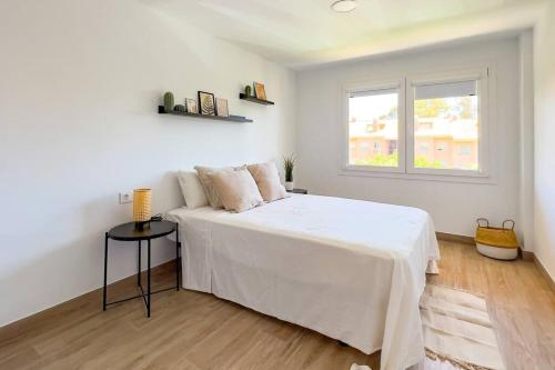 a white bedroom with a bed and a window at OleHolidays 624 Duplex Carib Playa 200 mts. playa in Marbella