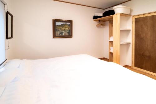 a bedroom with a white bed and a wooden cabinet at Immaculate Private Family Cottage with Hot Spring in Towada
