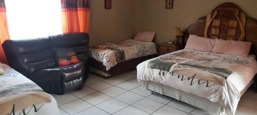 a living room with two beds and a leather chair at African Elephant Guesthouse in Germiston
