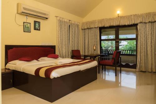 a bedroom with a bed and a table and a window at Wintergreen Water Front Resort in Tripunnittara