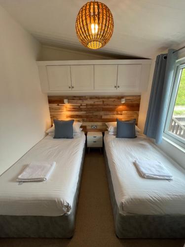 a room with two beds and a table and a chandelier at Cornish Beach Lodge in Torpoint