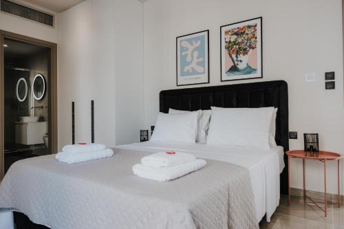 a bedroom with a white bed with two towels on it at Pearl Apartel in Volos
