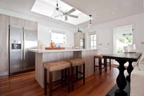 a kitchen with a refrigerator and a table with bar stools at Sugar Beach, A Viceroy Resort in Soufrière