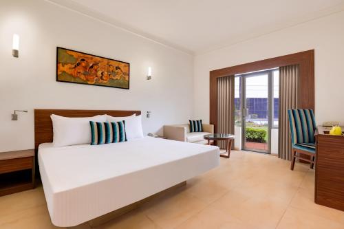 1 dormitorio con 1 cama blanca grande y escritorio en Lemon Tree Hotel, Aurangabad en Aurangabad