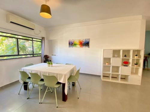 una sala da pranzo con tavolo e sedie bianchi di The Grand Hertzel a Tel Aviv