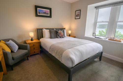 a bedroom with a bed and a chair and a window at Coolin View in Portree