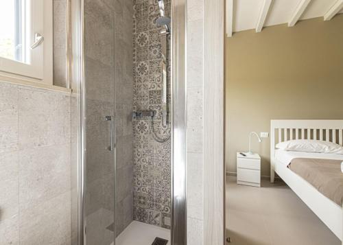a bathroom with a walk in shower next to a bed at B&B Villa Costanza in Lacona