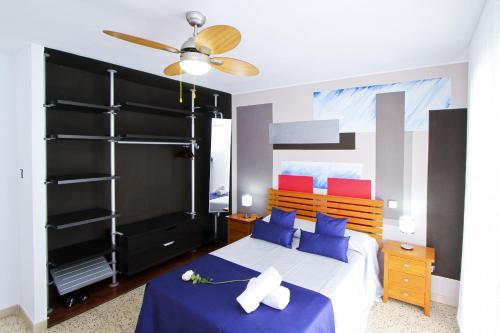 1 dormitorio con 1 cama con almohadas azules y ventilador de techo en New OKSANA PlanetCostaDorada, en Salou