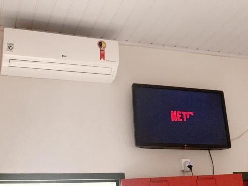 un televisor en una pared con un cartel de netflix en él en Suíte no centro histórico en Pirenópolis