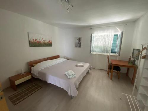 Schlafzimmer mit einem Bett, einem Tisch und einem Fenster in der Unterkunft Merla in Trogir