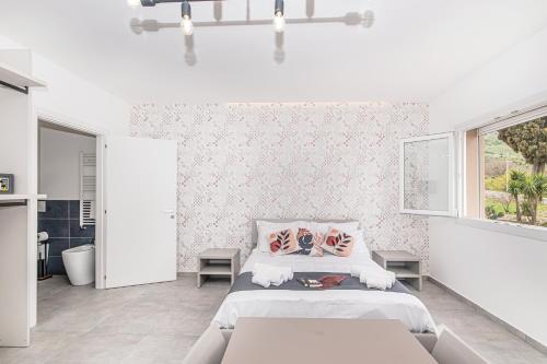 a white bedroom with a bed and a window at Coste Ponente Appartamenti Turistici in Ragusa