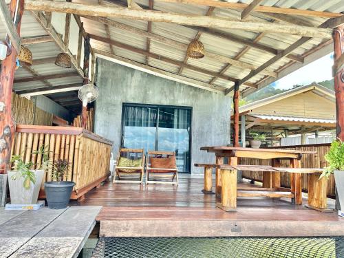a porch with a wooden table and a wooden bench at Lanta Sabai Day House in Ko Lanta