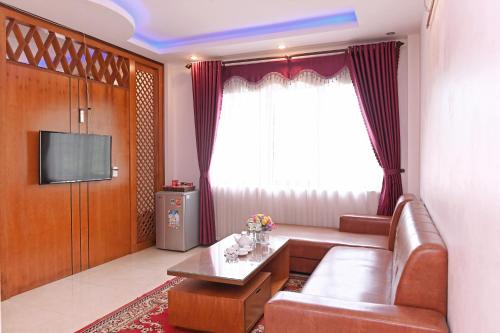 Khách sạn Hoàng Hà River Town في Hào Gia: غرفة معيشة بها أريكة وتلفزيون