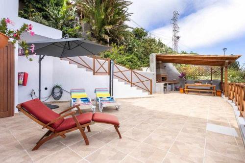 um pátio com 2 cadeiras, um guarda-sol e escadas em Casa en Anaga Senderismo naturaleza y desconexión em Santa Cruz de Tenerife