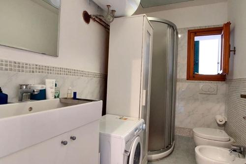 uma casa de banho com um lavatório e uma máquina de lavar e secar roupa em Mare Toscano em Riparbella