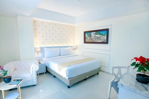 a bedroom with a bed and a couch and a chair at The Cube Hotel Malioboro, Azana Hotels Collection in Yogyakarta