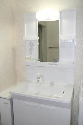 Private Inn Bambee في كوبه: حمام مع حوض أبيض ومرآة
