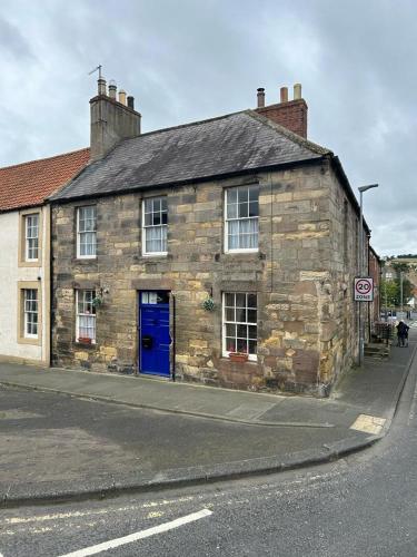 an old stone building with a blue door on a street at The Corner House Belford in Belford