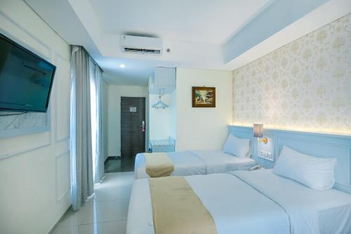 a hotel room with two beds and a flat screen tv at The Cube Hotel Malioboro, Azana Hotels Collection in Yogyakarta