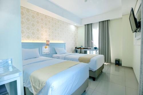 a hotel room with two beds and a television at The Cube Hotel Malioboro, Azana Hotels Collection in Yogyakarta