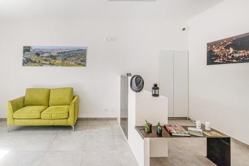 a living room with a yellow chair and a table at Coste Ponente Appartamenti Turistici in Ragusa