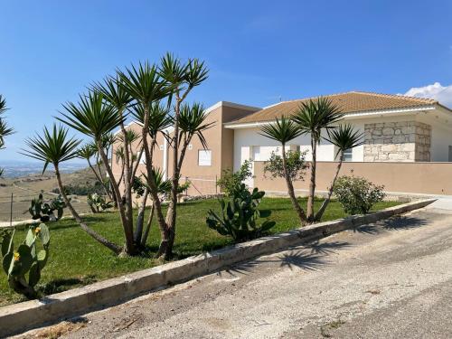 a house with palm trees on the side of a road at Coste Ponente Appartamenti Turistici in Ragusa