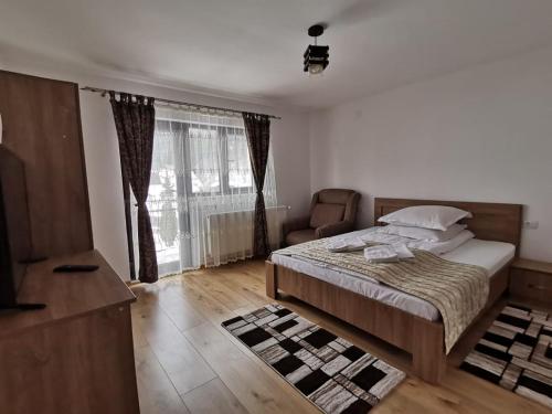a bedroom with a bed and a chair and a window at Casa Dana Olteanu in Moieciu de Sus