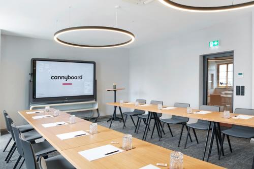 a conference room with tables and chairs and a projection screen at Hotel Hanauerhof in Appenweier