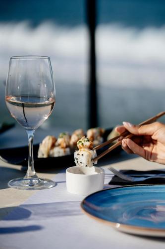 a glass of wine and a plate of food on a table at Infinity Blue Boutique Hotel & Spa - Adults Only in Hersonissos