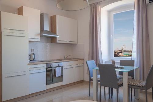 a kitchen with white cabinets and a table and a window at Captain Emo City Apartments in Pula