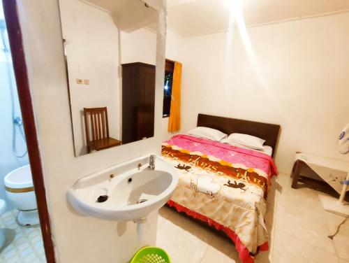 a bathroom with a sink and a bed with a mirror at Peno Homestay in Sumberbuluh