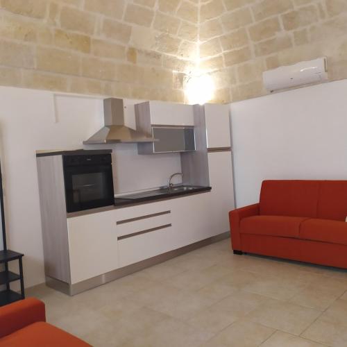 a living room with a red couch and a kitchen at STRADONE 132 in Gravina in Puglia