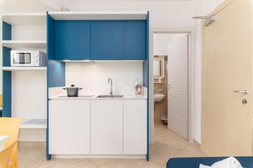 una cocina con armarios azules y fregadero en Calanca Apulian Residence, en Torre Santa Sabina