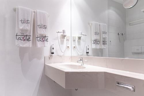 a white bathroom with a sink and a mirror at Taste Hotel Kulmbach in Kulmbach