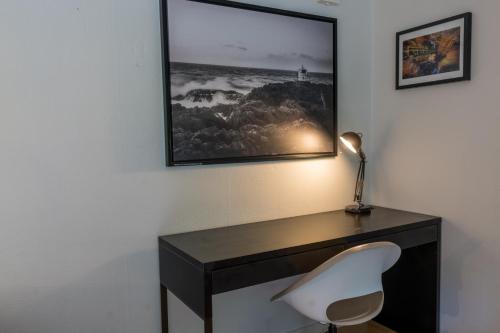 a desk with a white chair and a picture on the wall at Norra Häljaröd in Farhult